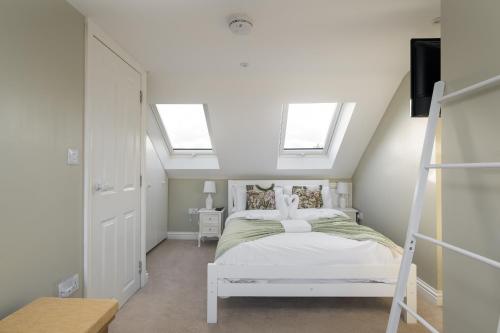 a bedroom with a white bed with two windows at Beautiful cottage style 3-bed By Valore Property Services in Loughton