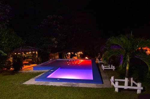 una piscina por la noche con dos bancos blancos alrededor en Cabaña Villa de Ada, en Gracias