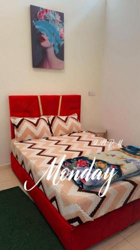 Una cama roja con un signo de feliz aniversario. en planet house, en Deroua