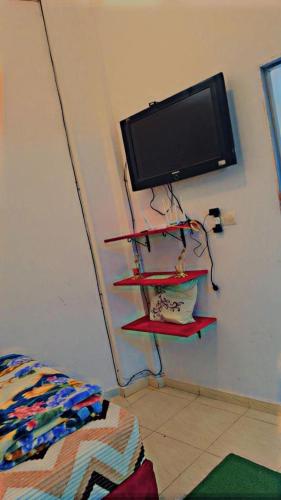 Zimmer mit einem TV an einer Wand mit Regalen in der Unterkunft planet house in Deroua