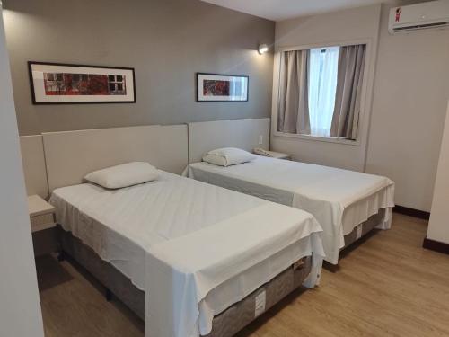 dwa łóżka w pokoju szpitalnym z oknem w obiekcie Flat Particular no Comfort Suites w mieście Brasília