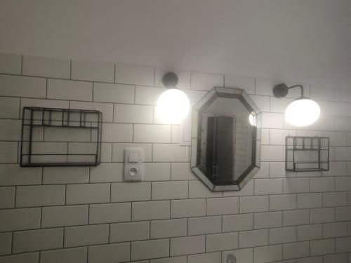 baño con 2 luces y espejo en la pared en Wieża Gniezno Apartament KRÓLOWA, en Gniezno