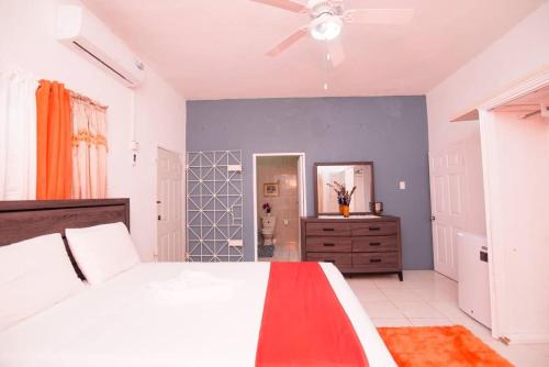 1 dormitorio con cama blanca y ventilador de techo en Suzette Guesthouse Accommodations en St Mary