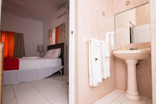 een badkamer met een wastafel en een slaapkamer met een bed bij Suzette Guesthouse Accommodations in St Mary