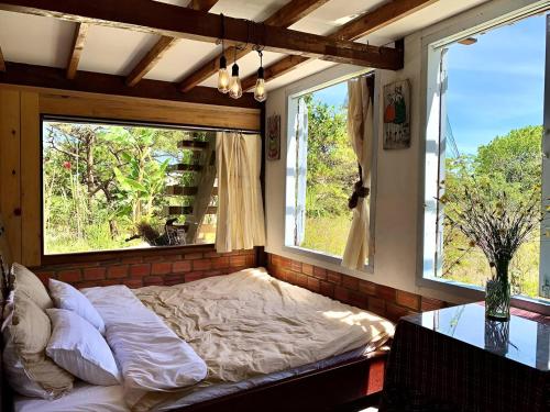 a bed in a room with two windows at Romantic house 2 on a pine hill Dalat in Da Lat