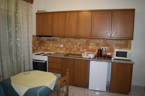 a kitchen with wooden cabinets and a table and a microwave at Isabela Apartments in Sarandë