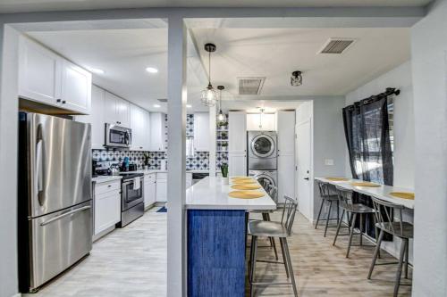 a kitchen with white cabinets and a kitchen island with chairs at Modern Home-Downtown-3 Bedroom- King Bed in Phoenix