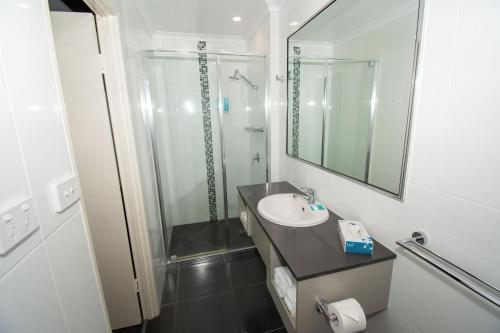 a bathroom with a sink and a shower and a mirror at Best Western Cattle City Motor Inn in Rockhampton