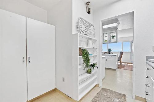 a white kitchen with white cabinets and a table at Beachfront 3 Bedroom 3 Bath In Seal Beal, Ca in Seal Beach