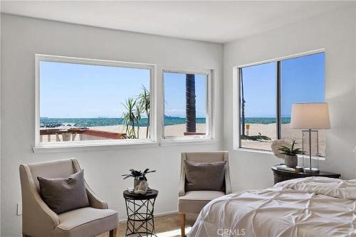 1 dormitorio con 2 sillas, 1 cama y ventanas en Beachfront 3 Bedroom 3 Bath In Seal Beal, Ca, en Seal Beach