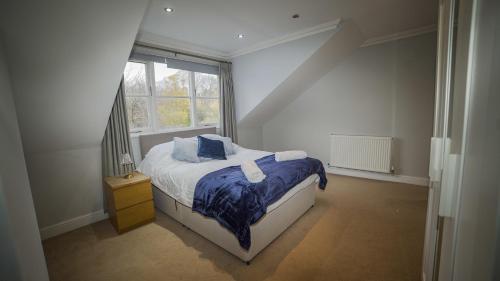 um quarto com uma cama com lençóis azuis e uma janela em Central 4 Bed Apartment em Leeds