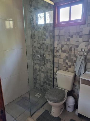 a bathroom with a toilet and a glass shower at Cabañas Jardines Santino in Bella Unión