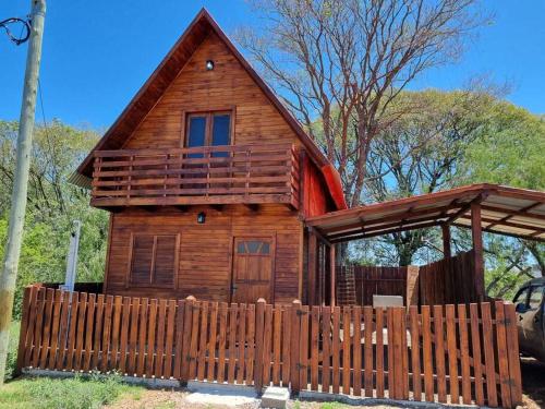 a wooden cabin with a fence in front of it at Cabañas Jardines Santino in Bella Unión