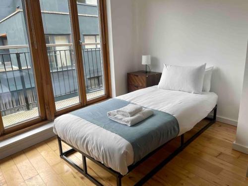 Bett in einem Zimmer mit zwei großen Fenstern in der Unterkunft Shad Thames by condokeeper in London