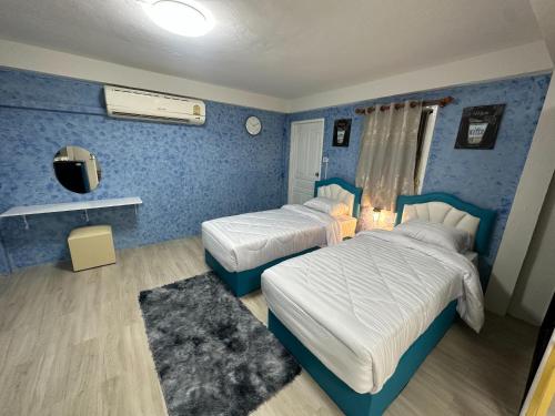 two beds in a room with blue walls at Hommie by De-A-Ga in Ban Bang Talat