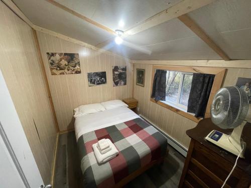 a small bedroom with a bed and a fan at NTJ Moose Lake Cabin in Bonnyville