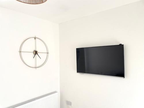 a living room with a wall clock and a tv at Chic Retreat: 2-Bed 1 Ensuite Oasis in Birmingham