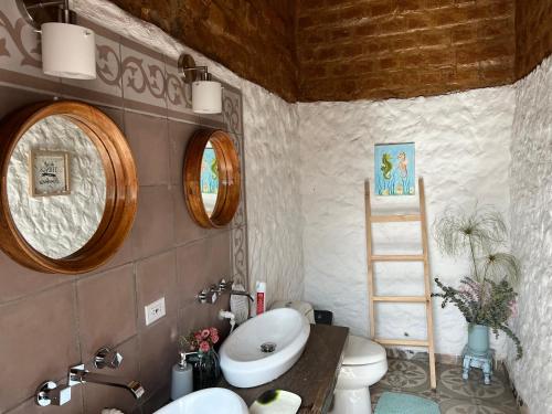 ein Bad mit einem Waschbecken, einem WC und 2 Spiegeln in der Unterkunft Casona Ananda in Firavitoba