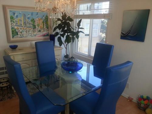 uma sala de jantar com uma mesa de vidro e cadeiras azuis em Centrally located; Walk anywhere! em São Francisco