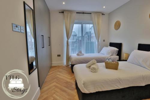a hotel room with two beds and a window at Newly-Built Urban Retreat by TTLG Stays in Rickmansworth