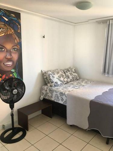 a bedroom with a bed and a painting of a woman at Apartamento MOBILIADO 200m do mar com vista mar, garagem, ar condicionado in Fortaleza