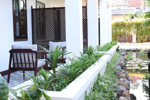 a patio with a pond and a chair on a house at Sunrise Garden House - Luang Prabang in Luang Prabang