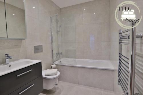 a bathroom with a tub and a toilet and a sink at Modern City Escape by TTLG Stays in Rickmansworth