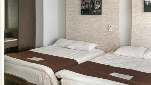 two beds in a small room with white sheets at Griffinbay Hotel in Busan
