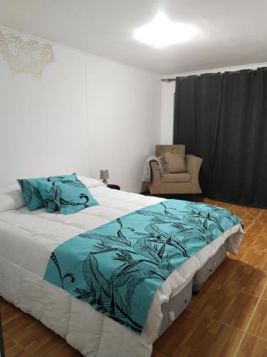um quarto com uma cama grande com lençóis azuis e uma cadeira em Hotel Hanau'eepe em Hanga Roa
