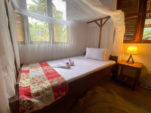a bedroom with a bed with a quilt and a window at Jumapili Beach Villa in Ushongo Mabaoni