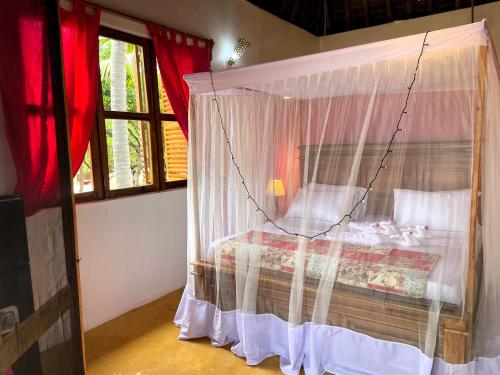 a bedroom with a bed with a canopy at Jumapili Beach Villa in Ushongo Mabaoni