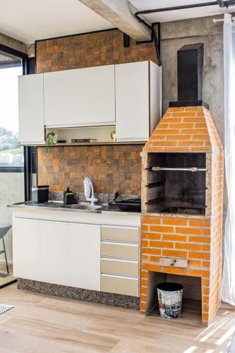 a kitchen with white cabinets and a brick oven at Uai House com jacuzzi, teto rooftop retrátil e colchão massageador in Poços de Caldas