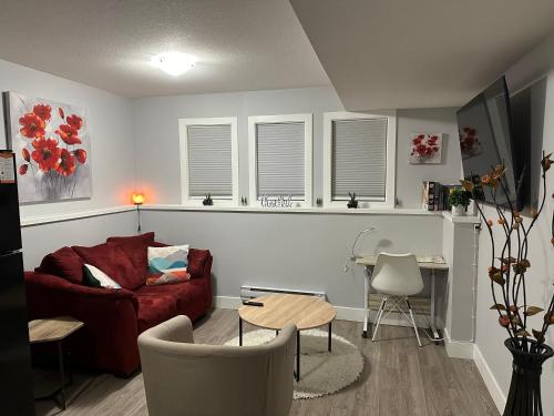 a living room with a red couch and a table at Exquisite Cozy Suite/full amenities in Kensington in Saskatoon