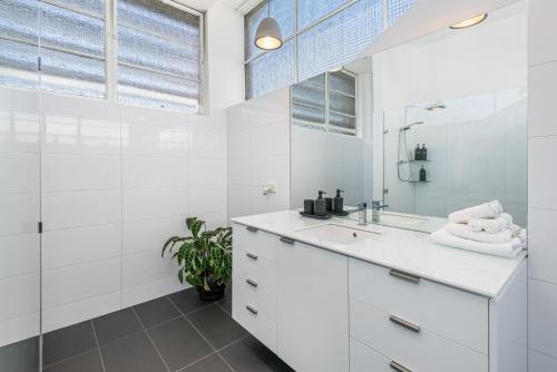 a white bathroom with a sink and a mirror at Bayne St Studio in Bendigo