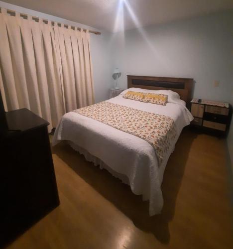 a bedroom with a bed with a white blanket and curtains at Casa Villa residencial in Maquegua