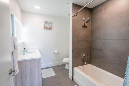 a bathroom with a tub and a toilet and a sink at Hollywood Panoramic Views, Pool, Gym & Free parking! in Los Angeles