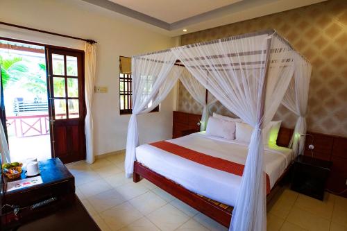 a bedroom with a bed with a mosquito net at Sea Star Resort in Phú Quốc