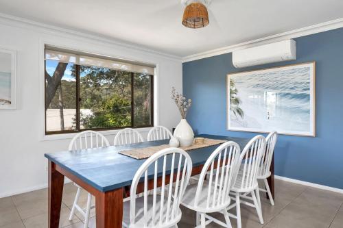 a dining room with a blue table and white chairs at Sandals at the Bay Upstairs sleeps 6 Hyams Beach in Hyams Beach