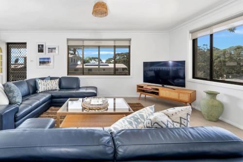a living room with blue couches and a tv at Sandals at the Bay Upstairs sleeps 6 Hyams Beach in Hyams Beach