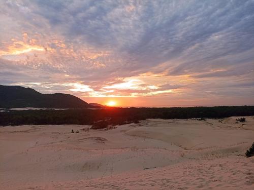 a sunset in the sand with the sun in the distance at Dunas Tiny House Casa 2 in Florianópolis