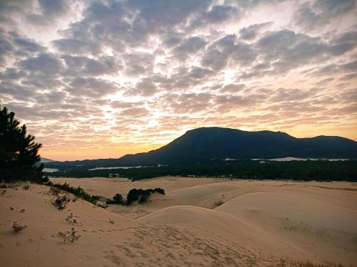 a sunset over the sand dunes with a mountain in the background at Dunas Tiny House Casa 2 in Florianópolis