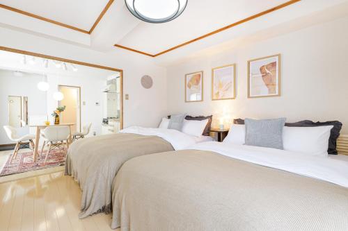 two beds in a white room with a table and chairs at The Dove House Quiet Apartment near Haneda Airport in Tokyo