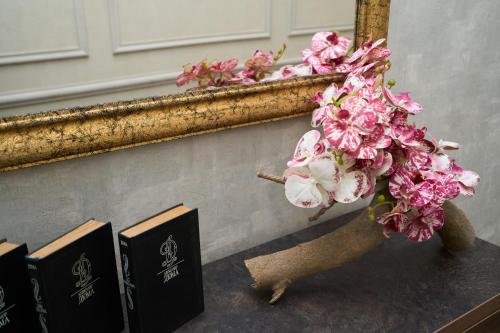 a vase filled with pink flowers next to a mirror at Zimmer Boutique Hotel in Baku