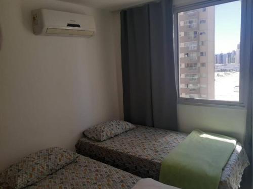a small room with two beds and a window at APT Perfeito, duas suítes no shopping Dfplaza in Brasilia