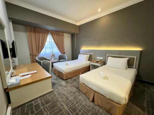 um quarto de hotel com duas camas e uma secretária em Permai Hotel Kuala Terengganu em Kuala Terengganu