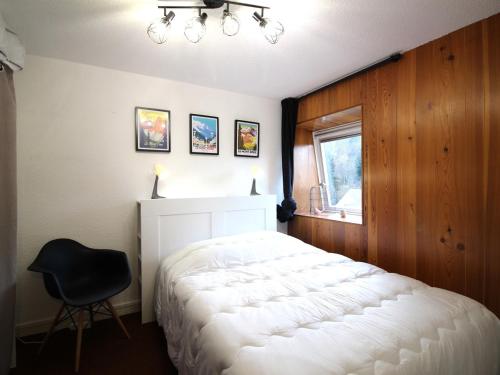 a bedroom with a white bed and a black chair at Appartement Mont-Dore, 2 pièces, 6 personnes - FR-1-415-149 in Le Mont-Dore