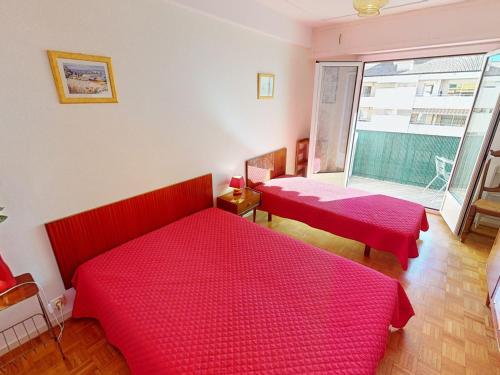 - une chambre avec 2 lits rouges et une fenêtre dans l'établissement Charmant 2P calme en centre-ville avec balcon, proche plages et commerces - FR-1-196-345, à Menton