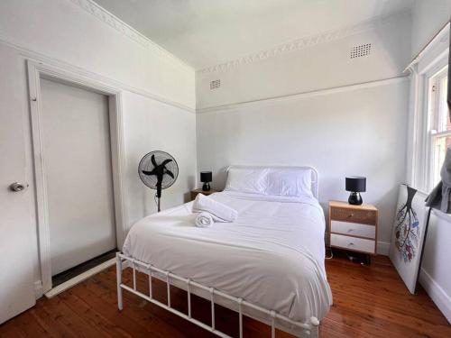 Cozy1 Bedroom Unit Near Maroubra Beach في سيدني: غرفة نوم بيضاء مع سرير أبيض ونافذة