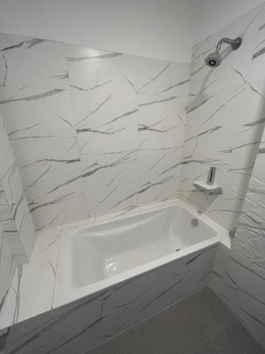a white bathroom with a tub and marble walls at O Abrigo in Panaji