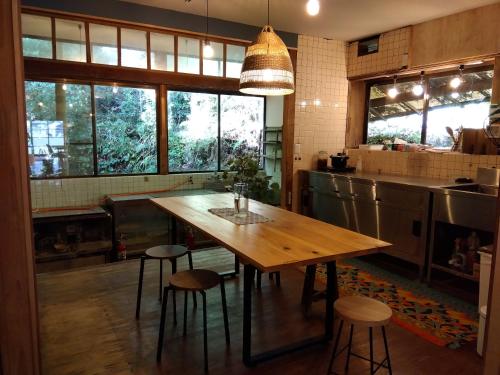 a kitchen with a wooden table and some windows at 朝食付き唐津里山の宿&ヨガ兎と亀 in Karatsu